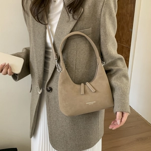 Close-up of khaki dumpling bag with soft matte texture and leather branding text