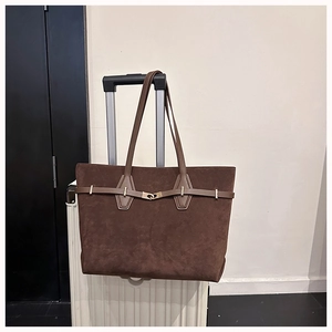 Macro shot of dark brown suede tote bag with decorative strap and metal buckle detail