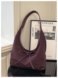 Detail of a vintage purple suede hobo bag with a decorative bow knot and leather trim