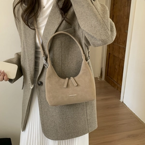 Detail of khaki suede hobo bag with white text logo styled on a grey wool coat