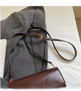 Détail d'un sac bandoulière en cuir marron foncé avec sangle et boucle dorée