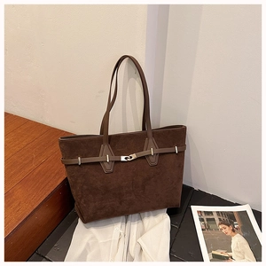 Detail view of large dark brown suede tote bag with silver buckle on wooden stairs