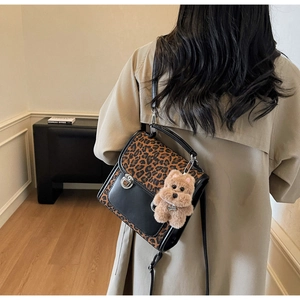 Détail du sac bandoulière léopard avec fermoir rotatif argenté et breloque ours en peluche