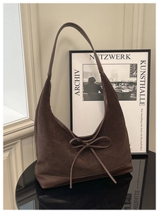 Detailed view of dark brown suede tote bag with leather trim and bow tie decoration
