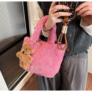 Close-up of pink faux fur bucket bag with a cute brown teddy bear charm and logo tag