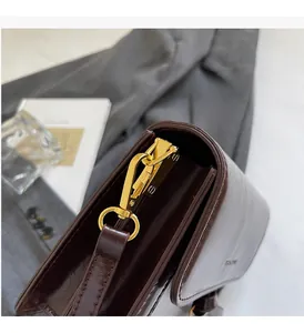 Détail du sac en cuir marron foncé avec finition brillante et fermoir en métal doré poli