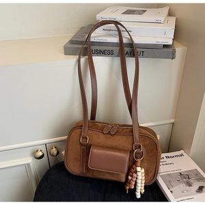 Detail of brown matte hobo bag with sleek front pocket and vintage beaded charm