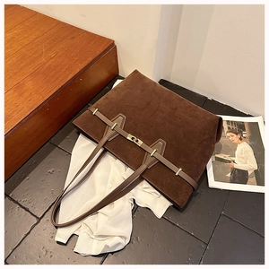 Detail of dark brown faux suede tote bag with golden twist lock and decorative strap