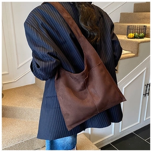 Minimalist brown suede tote bag with wide shoulder strap shown on model in retro style