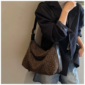 Close-up of leopard print hobo bag with wide adjustable black strap and gold buckle detail