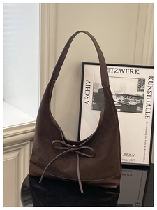Detail view of large brown suede tote bag with decorative bow and smooth texture