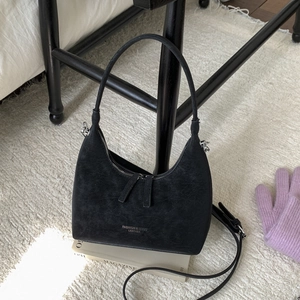Detail of black matte leather dumpling bag with dual metal zippers and logo text