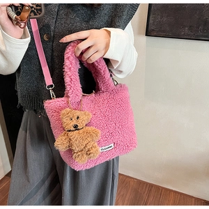 Detail of pink faux shearling bucket bag featuring a brown teddy bear plush charm