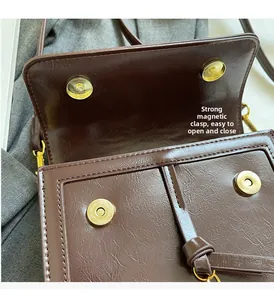 Détail des boucles magnétiques dorées et compartiments internes du sac en cuir brun
