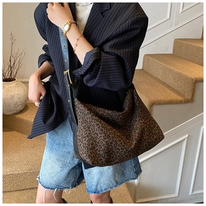Detail of hobo shoulder bag featuring leopard print fabric and black leather strap