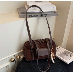 Detail view of brown matte leather shoulder bag with decorative vintage beads and front pocket