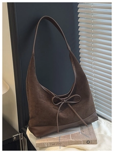 Detail of dark brown suede hobo bag with a delicate leather bow and smooth leather trim