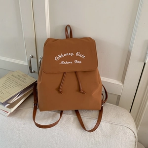 Close-up of caramel brown nylon drawstring backpack with white logo embroidery on flap