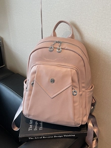 Minimalist pink pebble leather backpack with silver hardware on design books