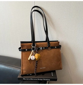Detail of vintage brown tote bag with suede texture and metal baseball themed charms