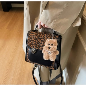 Détail du sac léopard avec charm ours en peluche marron et rabat en cuir noir lisse