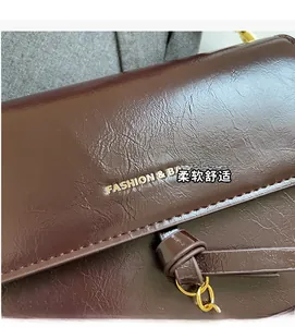 Détail du cuir brillant marron foncé avec chaîne dorée et logo de mode embossé