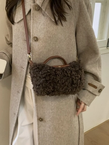 Mini brown faux shearling crossbody bag with leather handles shown on a wool coat