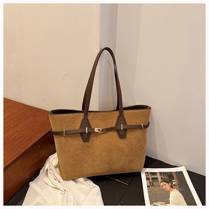 Close-up of brown suede tote bag with a dark leather strap and silver metal buckle detail