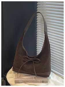 Close-up of the dark brown suede shoulder bag with an elegant bow and leather details