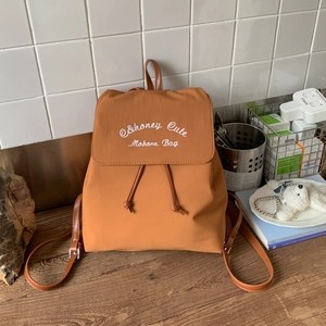Detailed shot of brown caramel backpack with honey cute embroidery and leather straps