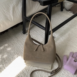 Detailed macro view of khaki dumpling bag with matte leather texture on a magazine