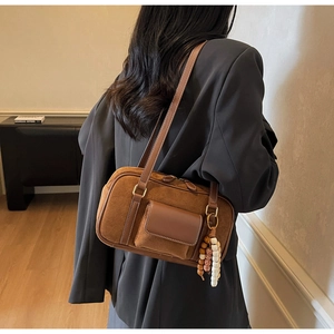 Detail of vintage brown suede shoulder bag with leather trim and wooden bead charm