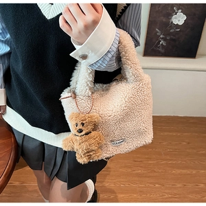 Detail of plush off-white bucket bag featuring a cute brown bear charm and brand label