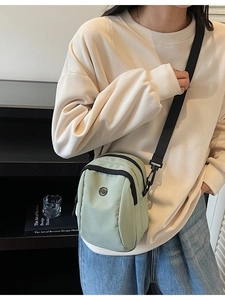 Light green nylon crossbody phone bag with multi-layer zippers and adjustable strap
