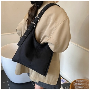 Detail of adjustable wide shoulder strap with silver eyelets on black suede bucket bag