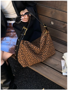 Detailed view of leopard print tote bag with black leather strap and gold buckle