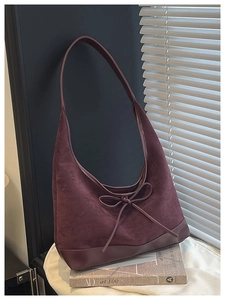 Detail of dark purple suede tote bag with elegant bow tie decoration and smooth base