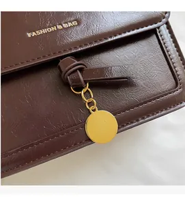 Macro d'un sac en cuir synthétique marron brillant avec pendentif doré et texte fashion