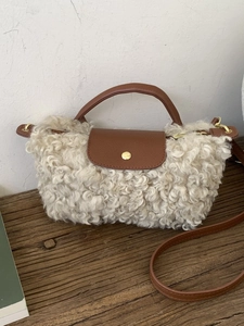 Plush beige faux fur crossbody bag with brown leather handles and gold clasp detail