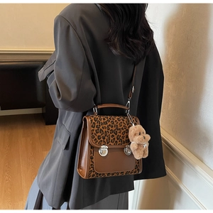 Close-up of leopard print retro crossbody bag with dual silver buckles and bear charm