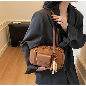 Detail of brown vintage suede shoulder bag with wooden bead tassel on model
