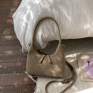 Detail of light brown retro dumpling bag with textured faux leather and strap