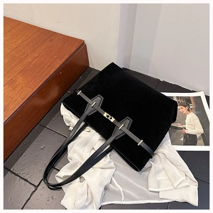 Detail of black suede tote bag with gold metal buckle on white shirt and magazine