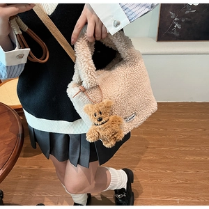Detail shot of beige faux fur bucket bag featuring a cute plush bear charm and side tag