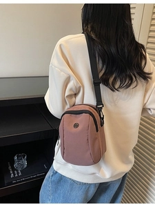 Morandi pink canvas crossbody bag with adjustable strap shown on a model outfit