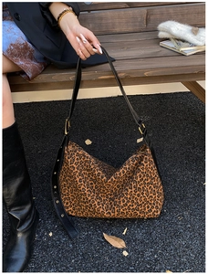 Detail of leopard print tote bag with black leather shoulder strap and metal buckle adjustment