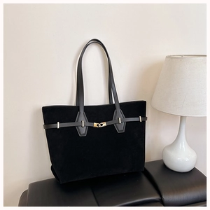 Detail of matte black tote bag showing gold twist-lock closure and suede leather texture