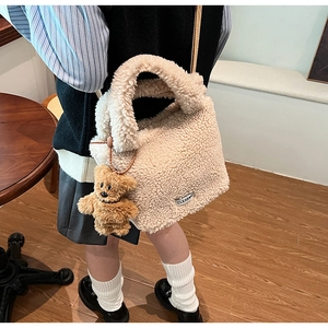 Beige faux fur bucket bag with bear pendant worn by a model in a cozy cafe setting