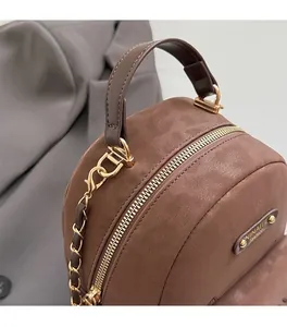 Close-up of premium brown faux leather texture with golden zipper and brand logo plaque