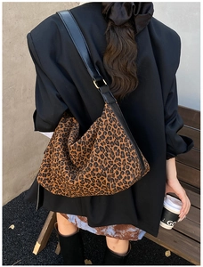 Detail of leopard print tote bag featuring black leather strap and gold metal buckle